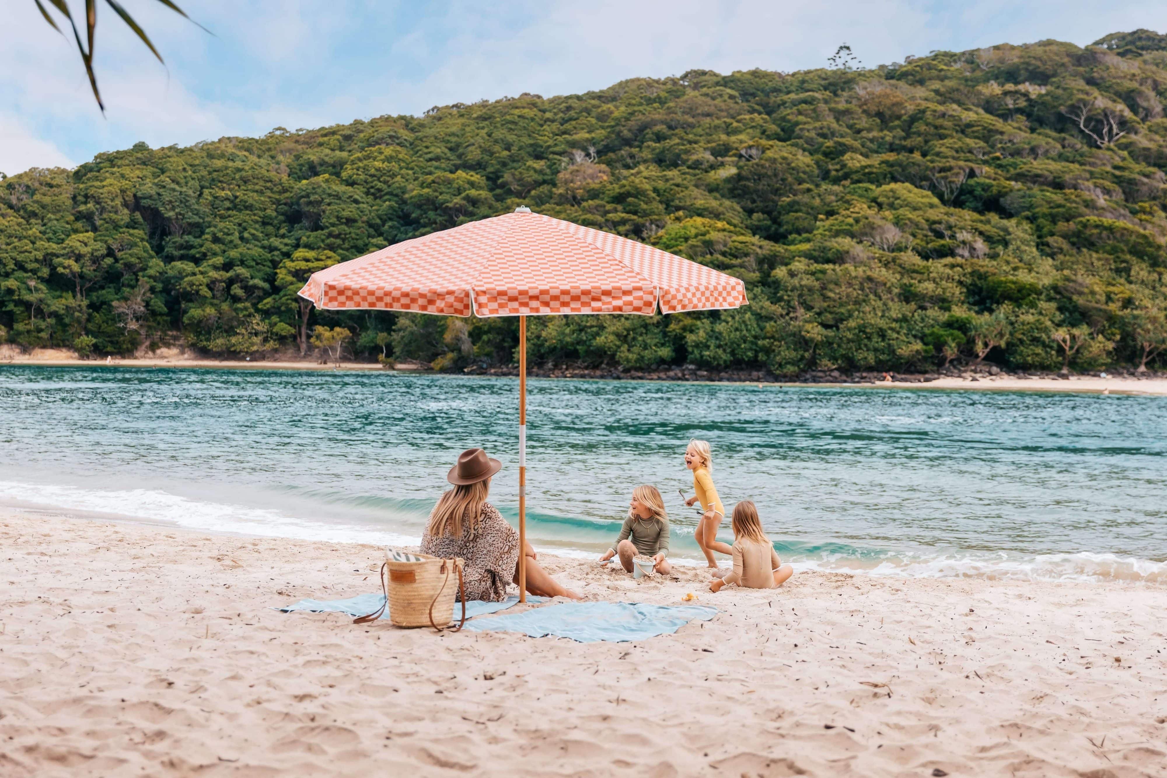 Mother and kids playing on the sand next to the Tallebudgera creek