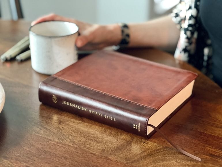 a person sitting at a table with a book and a cup