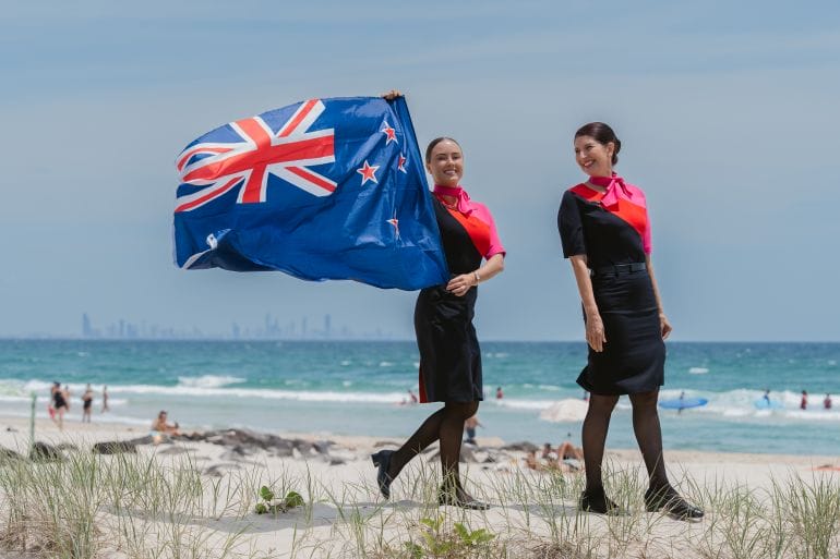 Qantas Cabin Crew standing on Kirra Beach with New Zealand Flag